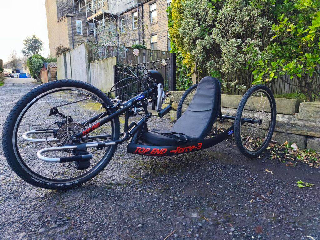 Accessible TOP End Force 3 handcycle parked outdoors—empowering disabled people to enjoy cycling and nature with our community group.